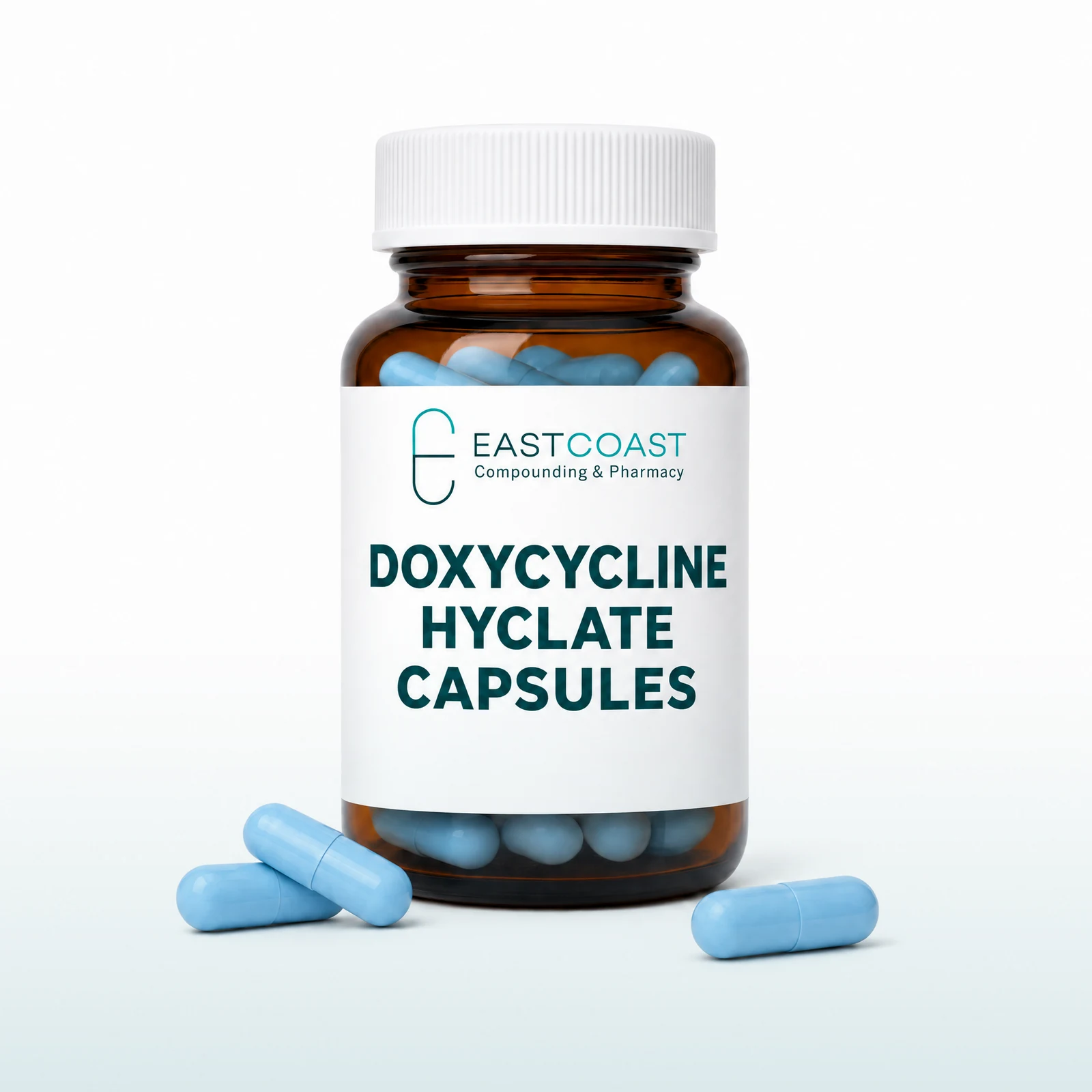 Doxycycline hyclate capsules in an amber pharmacy vial with East Coast Compounding & Pharmacy label, blue capsules beside it (illustrative image)