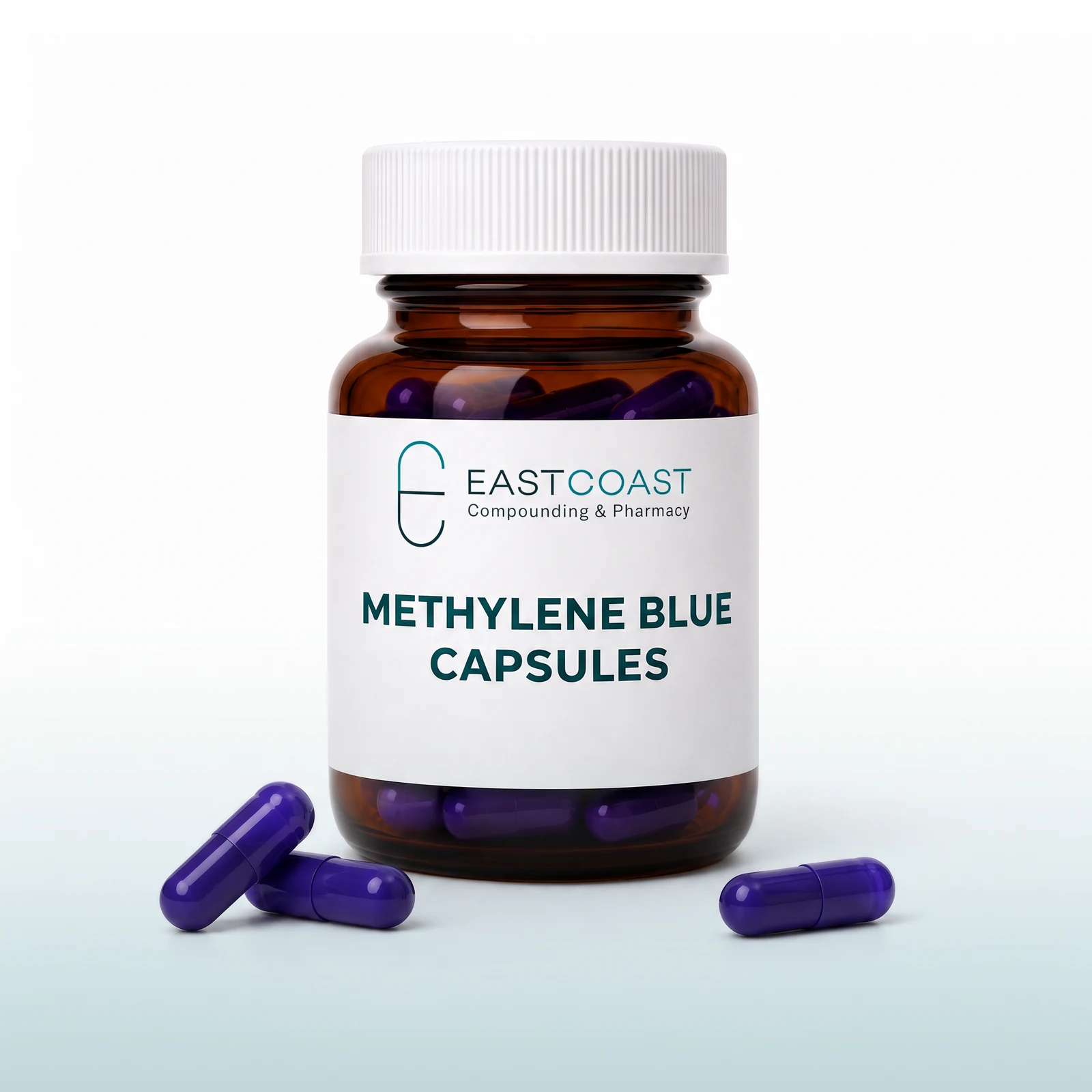 Methylene blue capsules in an amber pharmacy vial with East Coast Compounding & Pharmacy label, three blue capsules beside it (illustrative image)